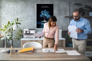 Two economists looking at documents and working together in bank office